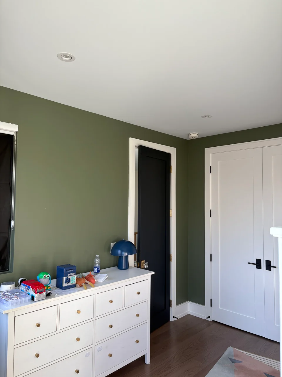 Before: olive green bedroom walls with white door and baseboards