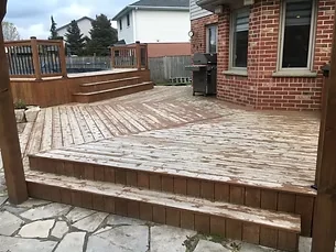 Before: worn deck boards and steps beside a red brick house