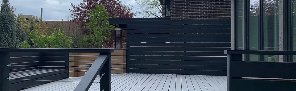 Grey deck boards with black railings and horizontal privacy screen