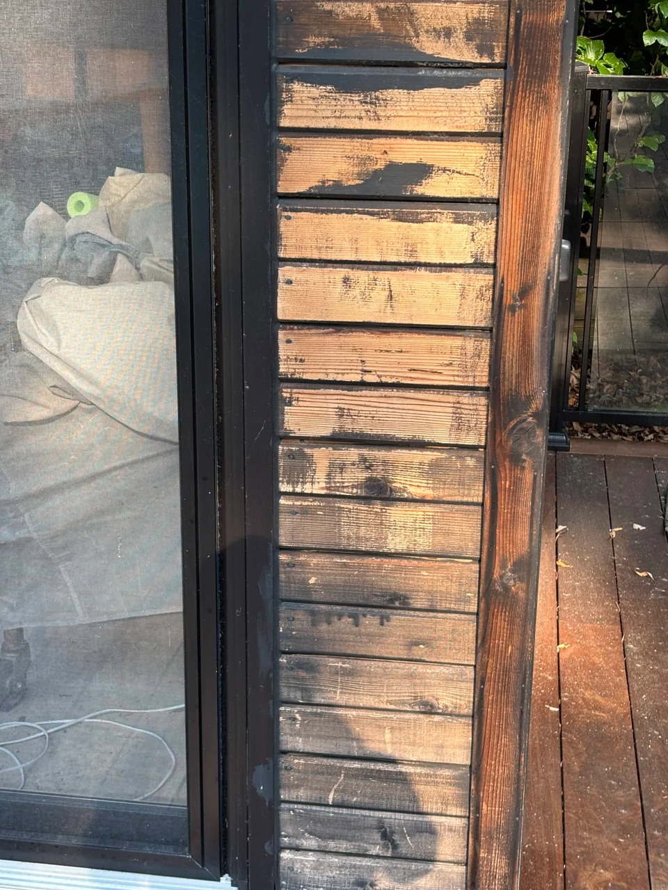 Before: worn wood boards and dark framing beside a sliding glass door