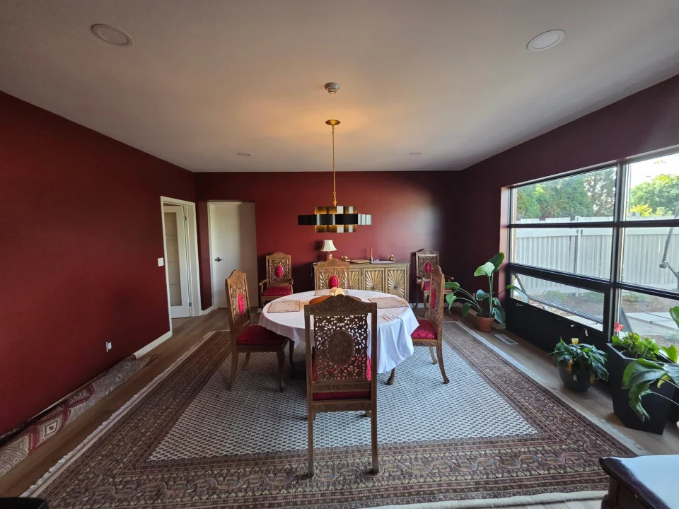 After: burgundy dining room walls with white trim and a hanging light