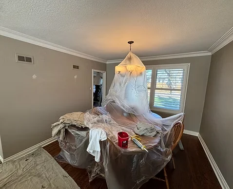 Dining room preparation with table, chairs and pendant light covered