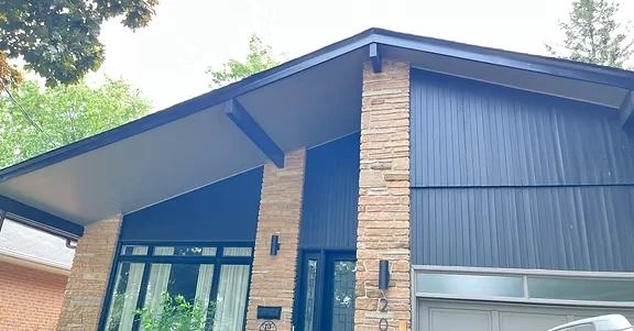 Blue exterior siding and roof trim beside a brick chimney