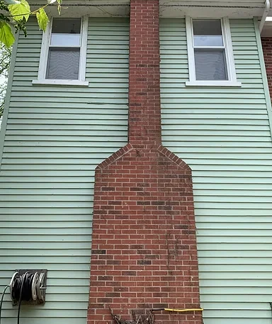 After: pale green siding and white window trim around a brick chimney