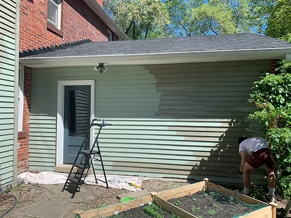 Green exterior siding on a rear addition during surface preparation
