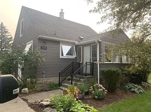 After: darker upper siding and clean window trim on the brick home