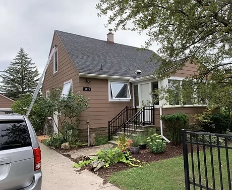 Before: light upper siding and white trim on a small brick home