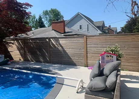 Before: weathered wood privacy fence beside a swimming pool