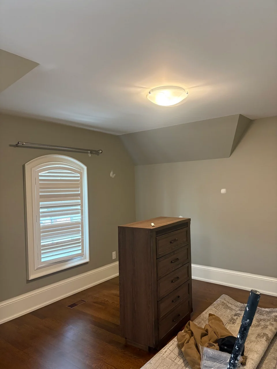 Finished greige bedroom walls with white trim around an arched window