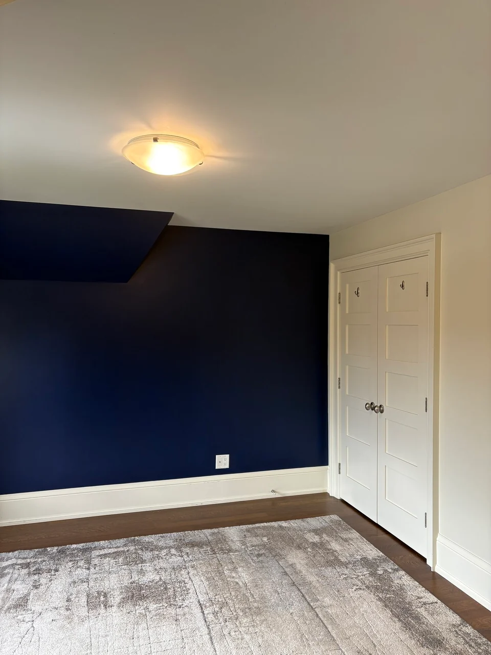 Navy bedroom accent wall meeting white closet doors and baseboards