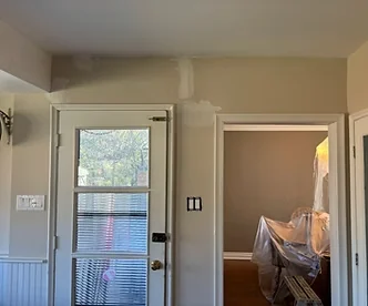 Interior wall patches around a window and white trimmed doorway