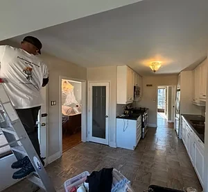 Painter on a ladder preparing the kitchen wall above a doorway