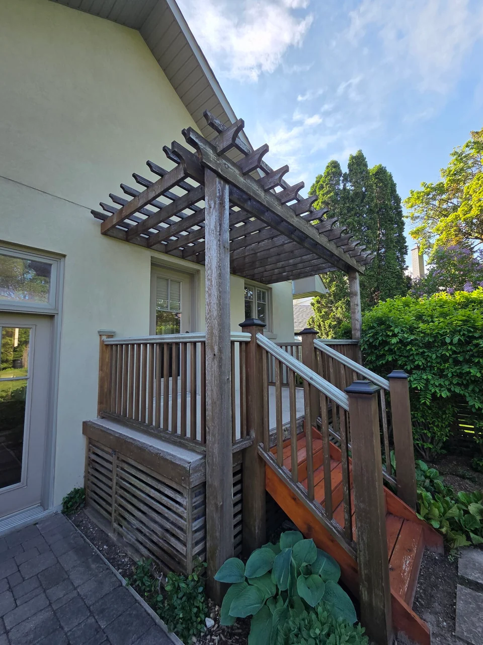 Before: weathered grey deck and pergola beside a light coloured house