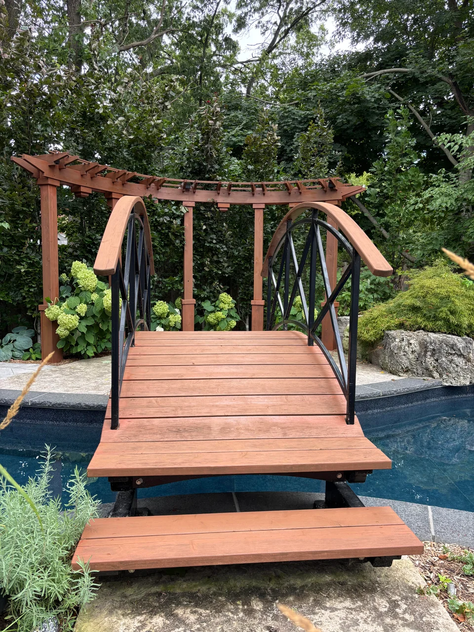 Front view of stained pool footbridge boards, steps and handrails
