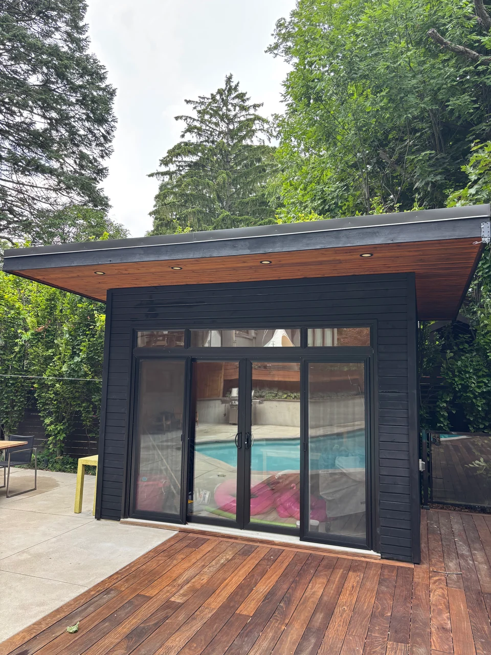 After: dark poolhouse trim and refreshed wood deck beside the pool
