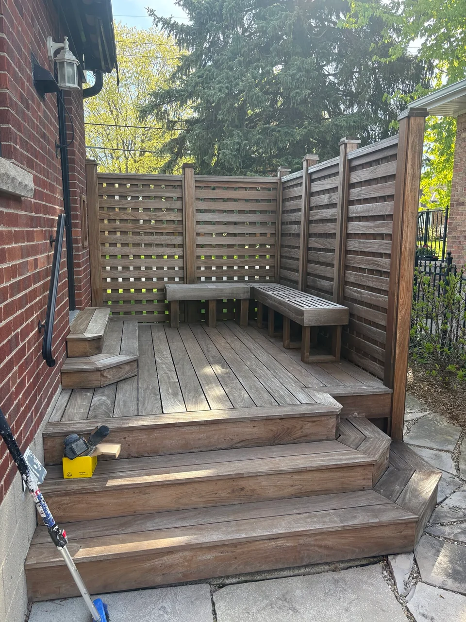 Before: weathered deck steps with built-in bench and privacy screen